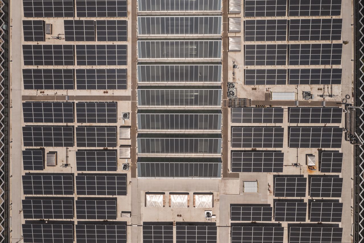 Mastering the First Impression: Your intriguing post title goes here A high-angle drone shot capturing a grid of solar panels on a large industrial rooftop, showcasing renewable energy.